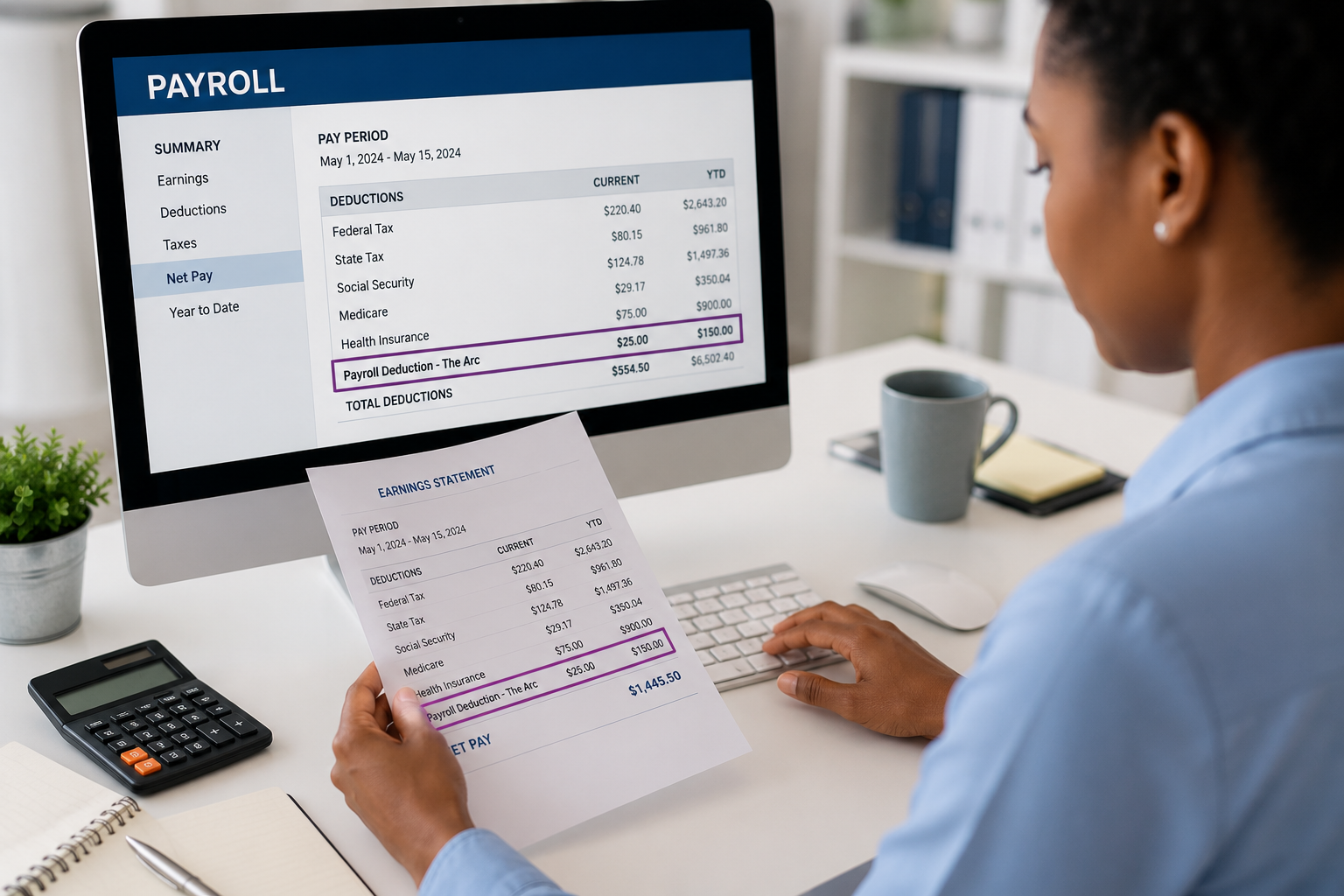 Employee reviewing a pay statement and payroll deductions on a computer screen in an office setting.